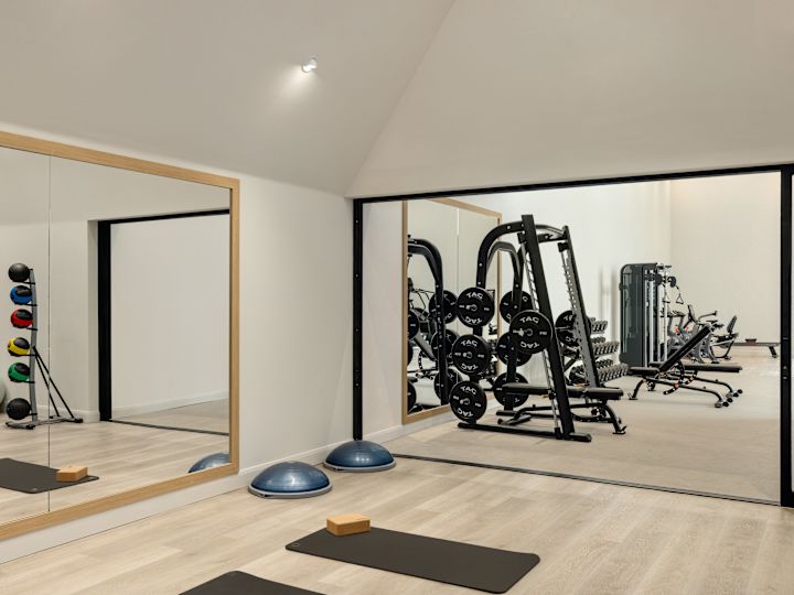 Hotel fitness center with floor to ceiling mirror, yoga mats, and weight machines