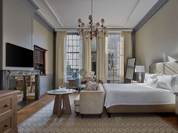 Large Bed, and Lounge Area in a Suite with TV and Large Windows