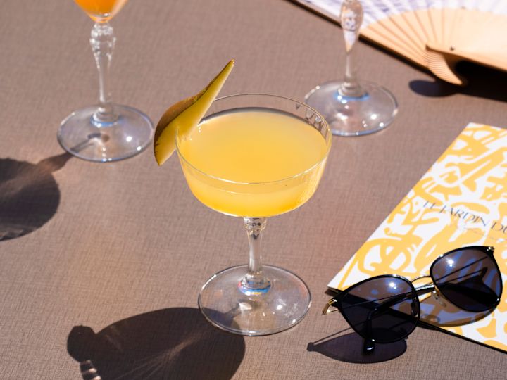 Sluneční brýle a nápoje na stole v hotelu Jardin du Trianon