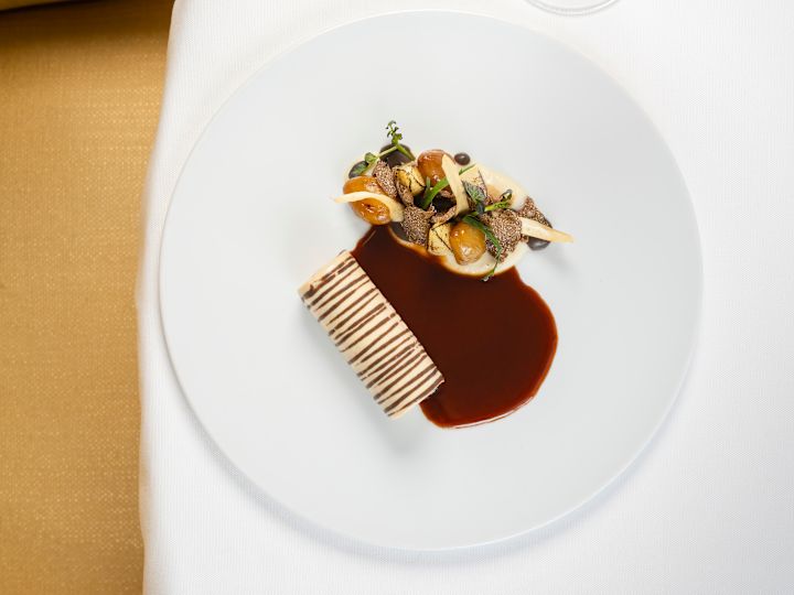 Ein Drink und ein Teller mit Speisen auf einem Tisch im Restaurant "Gordon Ramsay au Trianon"