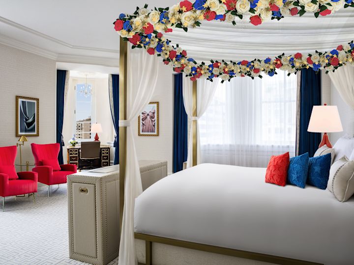 Large Bed with a Canopy Decorated with Flowers in a Suite with Seating Area