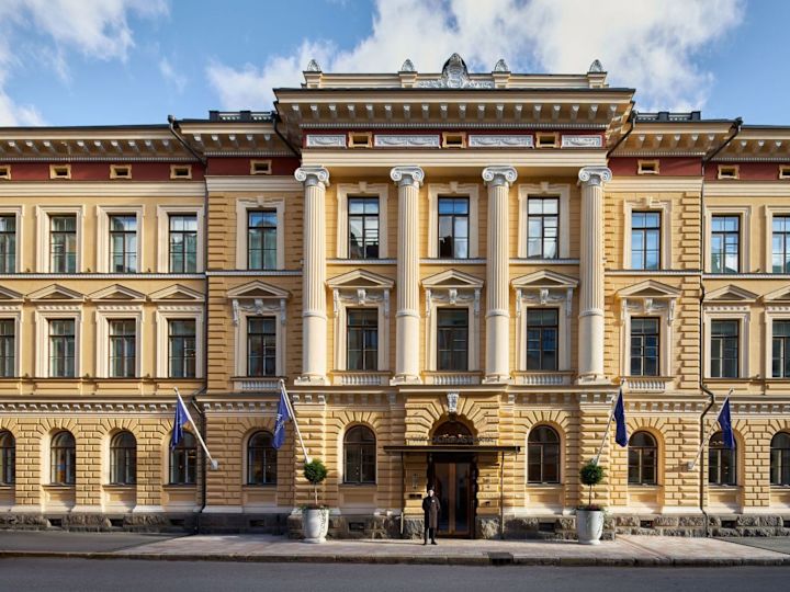 Esterno hotel con bandiera che sventola e portiere fuori dalla proprietà