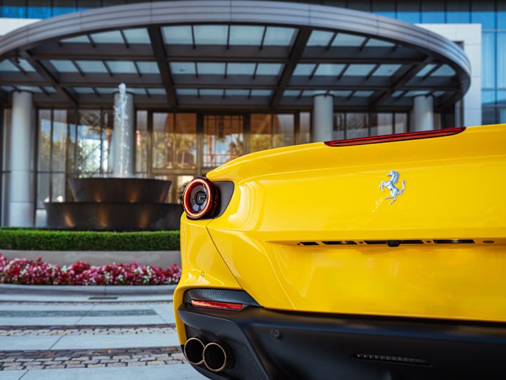 eksterior hotel, mobil kuning di depan gedung, dan air mancur