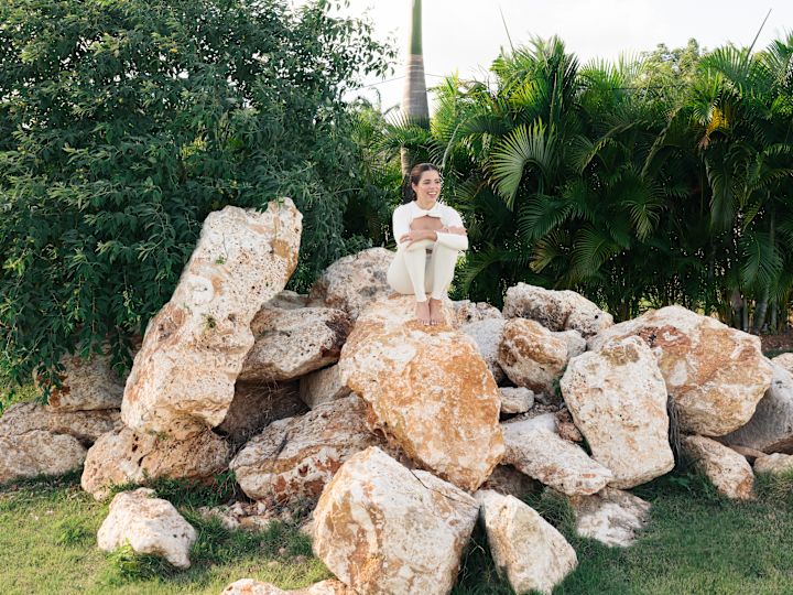 A Woman Sitting on a Pile of Rocks in a Courtyard with Palm Trees