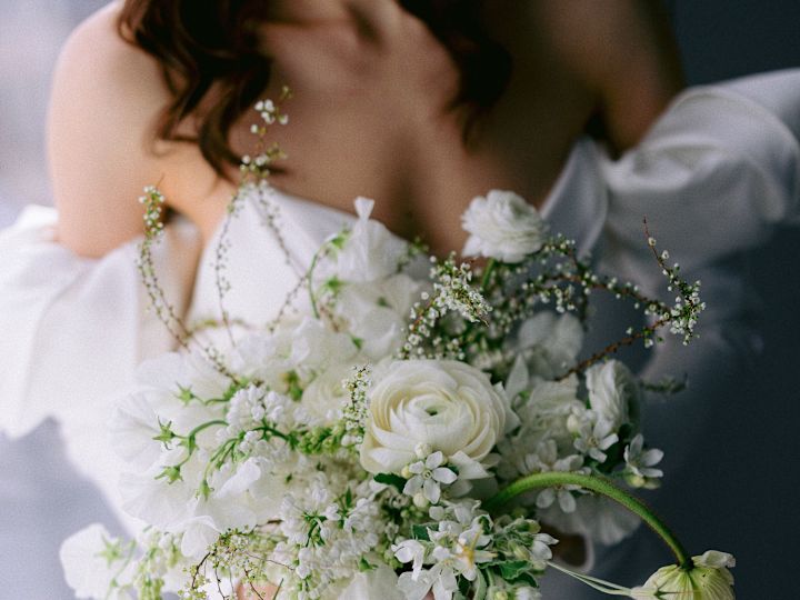 Bride sitting on window holdihng bouquet