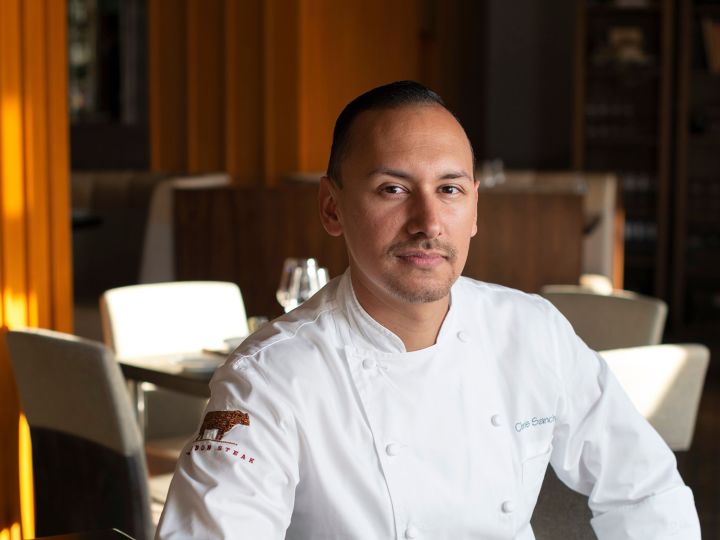 Photograph of Chef Chris Sanchez Sitting at a Table in a Restaurant