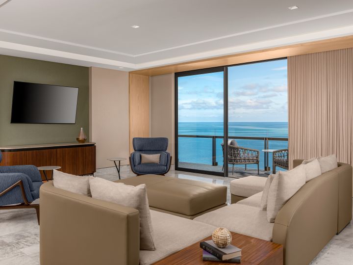 Suite living room with sofa, chairs,balcony access and wall mounted TV