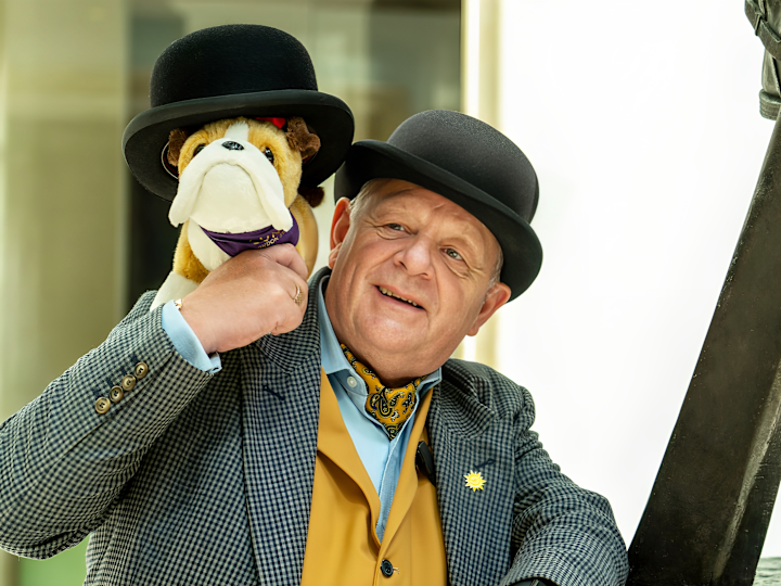 Concierge Holding a Stuffed Dog Wearing a Hat