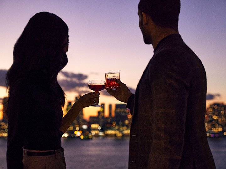 Man and woman looking out over water, raising glasses