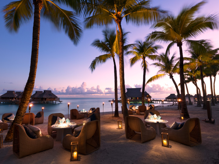 Outdoor Patio Area with Armchairs, Tables and Palm Trees at Dusk
