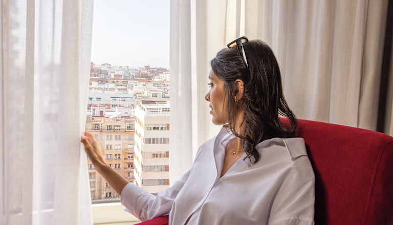 Mujeres sentadas en una silla cómoda mirando desde la ventana de la habitación