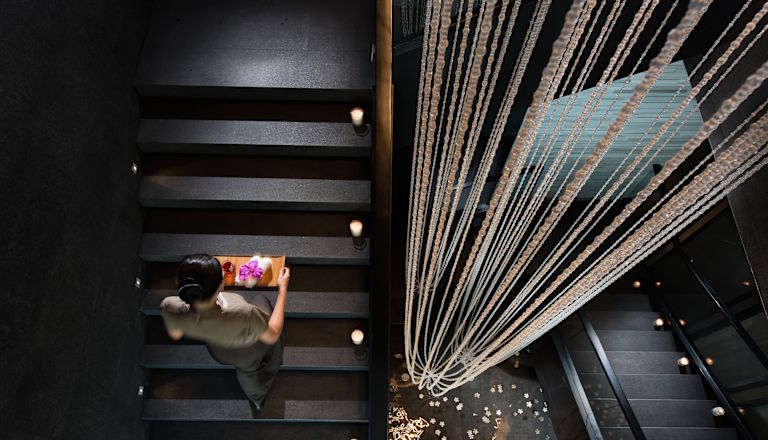 Woman Carrying Spa Products on a Staircase