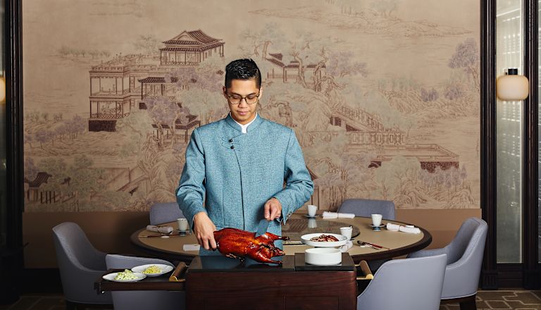 고기를 자르기 위해 테이블에 서 있는 직원