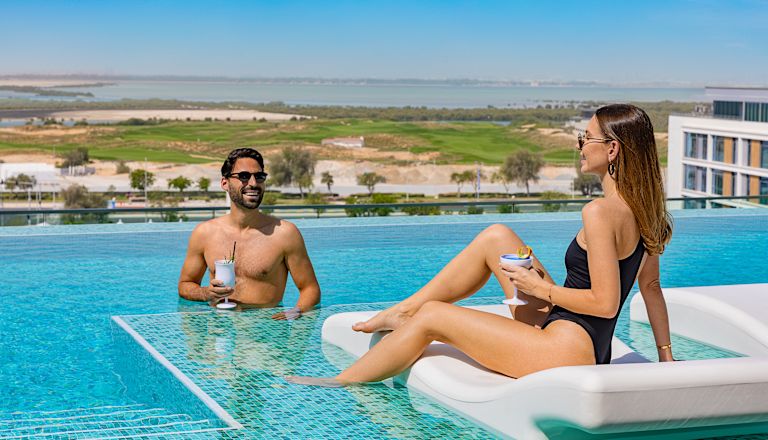 Frau und Mann am Swimmingpool mit Drinks
