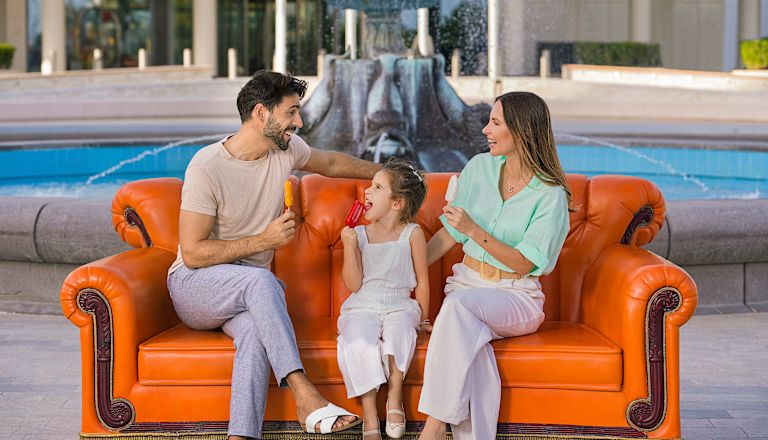 Familie auf orangefarbenem Sofa im Freien