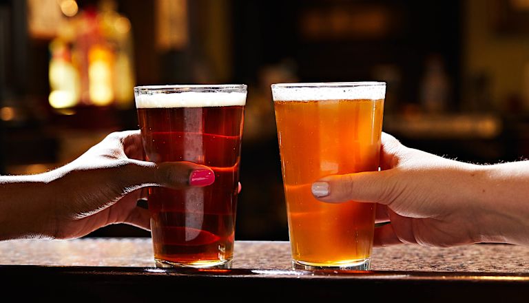 Primo piano di due persone che sbattono bicchieri di birra