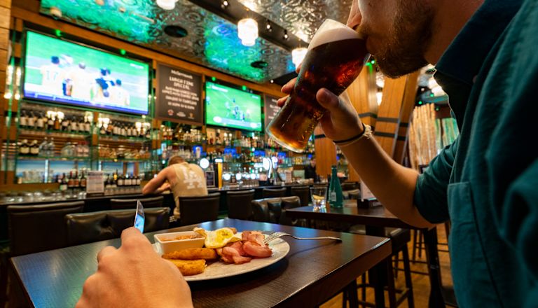 guest drinking beer at bar with a plate of food