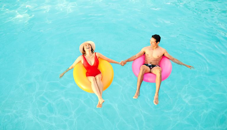 Man and woman in pool, floating on rubber rings