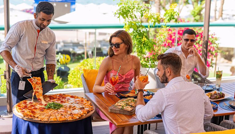 Waiter Serving Pizza to a Family at Vero Restaurant