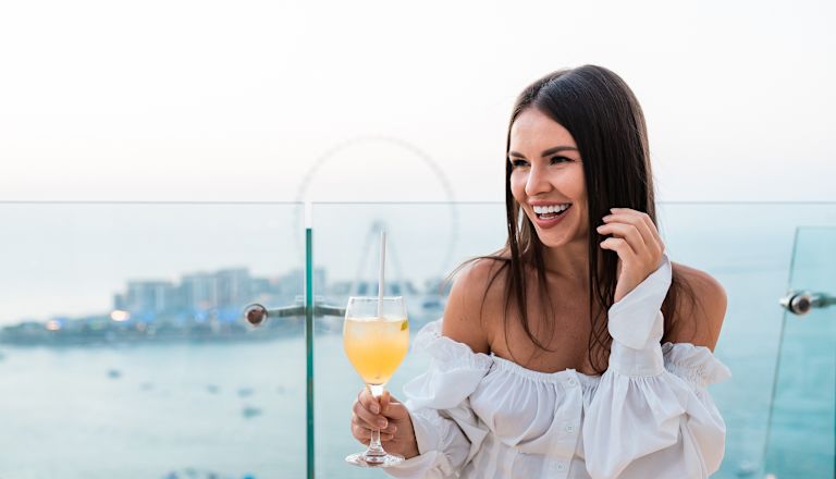 Woman holding a drink on the Pure Sky Lounge terrace