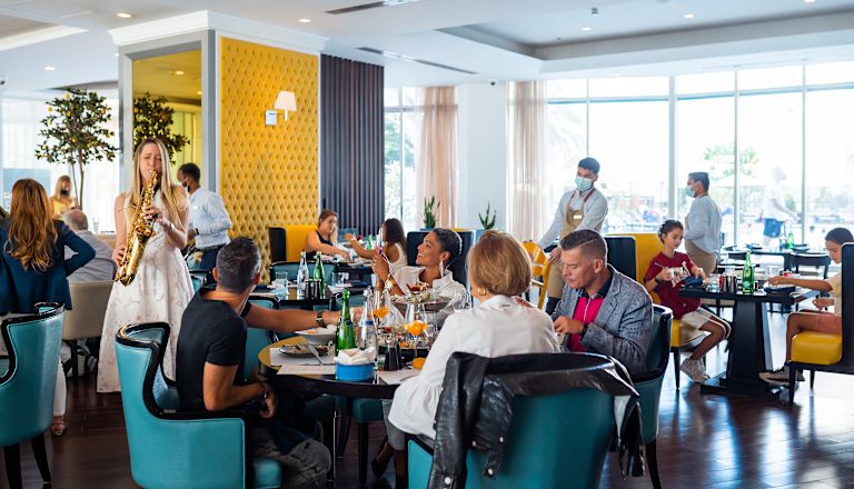 People eating in Vero restaurant with girl playing a saxophone