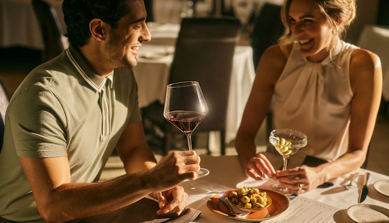 Pareja disfrutando de una bebida y una comida en una mesa