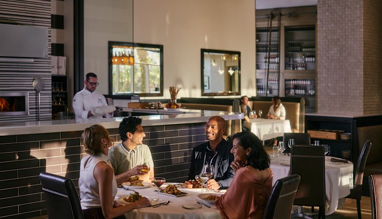 Grupo de personas sentadas en el restaurante, con un miembro del personal detrás del bar