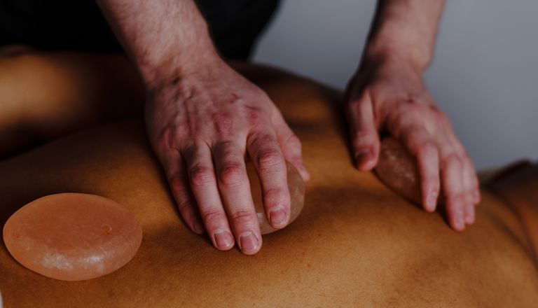 Pessoa recebendo uma massagem com pedras salgadas no spa