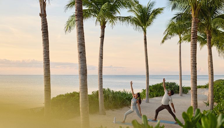 Man and woman practicing yoga on the beach