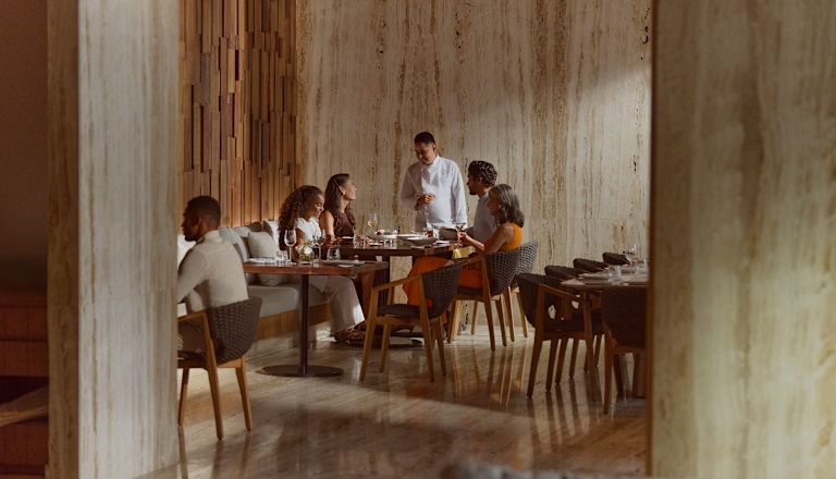 Chef or waiter speaking to family consisting of father, mother, daughter and grandmother