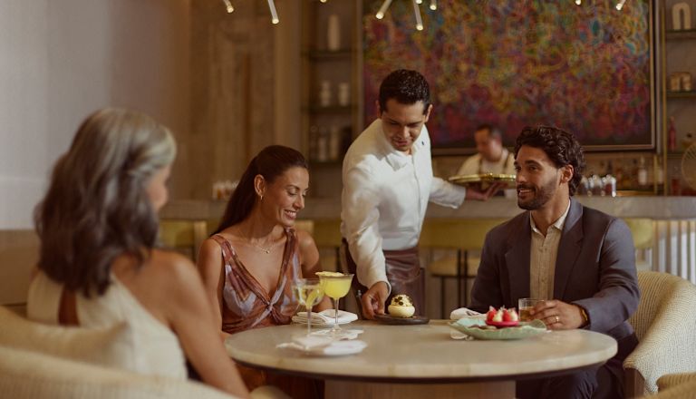 Two women and one man having drinks and desserts in Peacock Alley