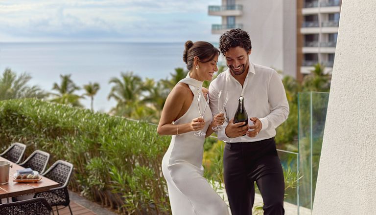 Bride and Groom about to open champagne with view of sea