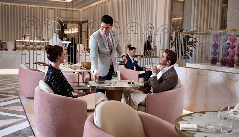 Người đàn ông và phụ nữ ngồi trong khu vực nhà hàng với đồ ăn và đồ uống
