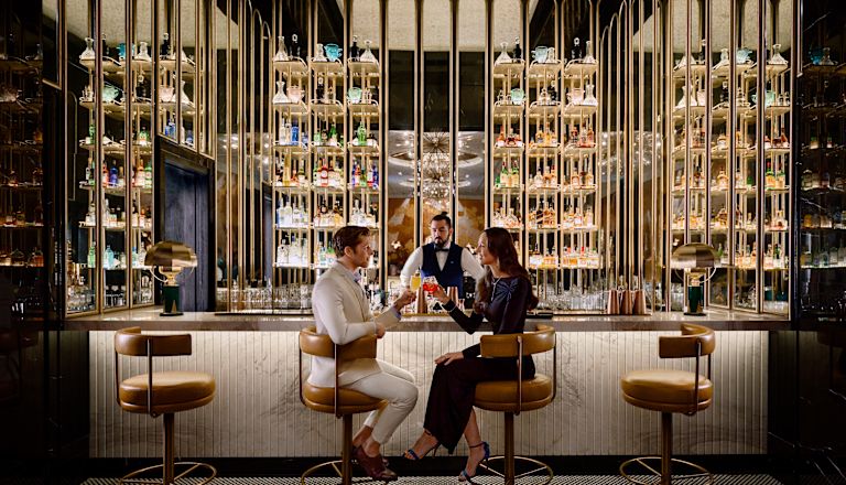 Khu vực quầy bar có người đàn ông và phụ nữ ngồi trên ghế đẩu