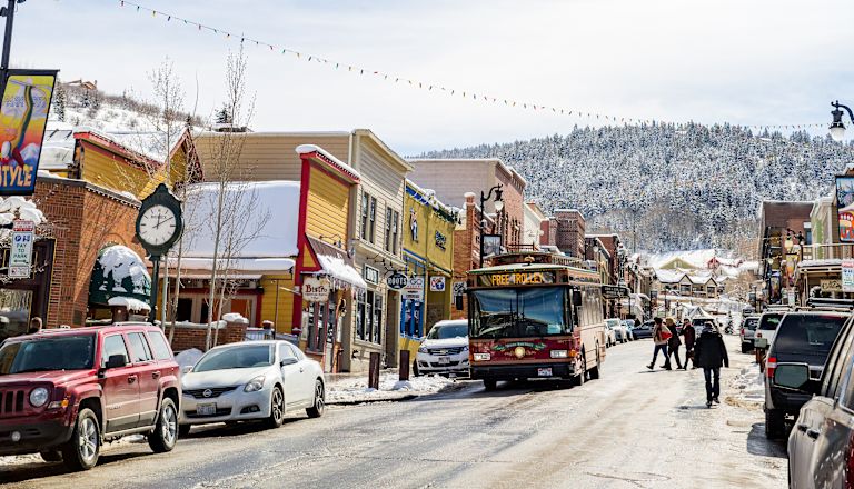 People Walking on Busy Main Street In a City with Mountains in Background