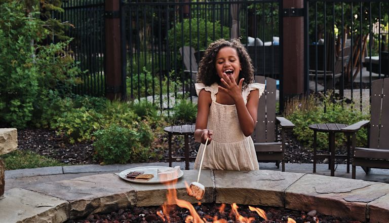 Girl Enjoying a Making Smores in a Courtyard Firepit