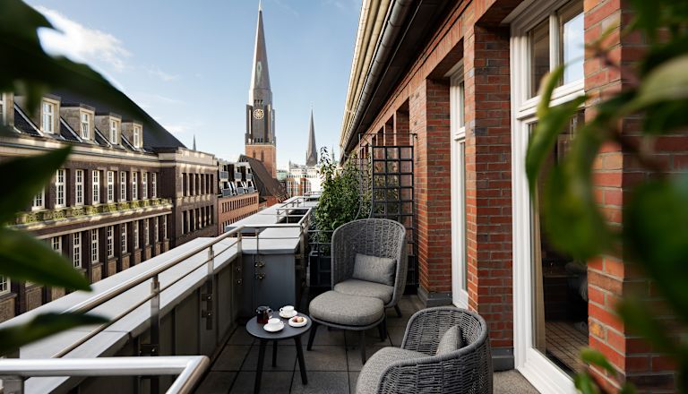 Balkon mit Sitzbereich in einer Hotelsuite mit Stadtblick