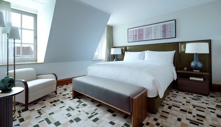 Zimmer mit Bett, Nachttisch, Lampe, Clubsessel