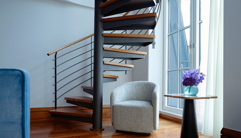 Zimmer mit Wendeltreppe, Clubsessel, Tisch mit Blumen