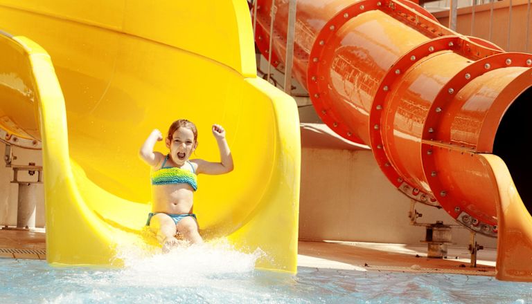 Glückliches kleines Mädchen auf Wasserrutsche des Wasserparks