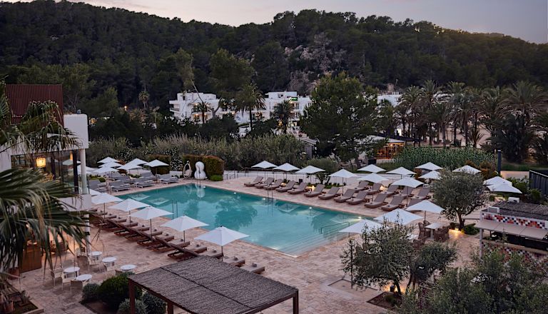 Outdoor Pool Area with Lounge Chairs under White Umbrellas at Sunset