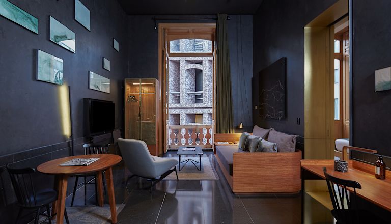 La zona lounge della camera con divano, TV e doppie porte si apre sul balcone.