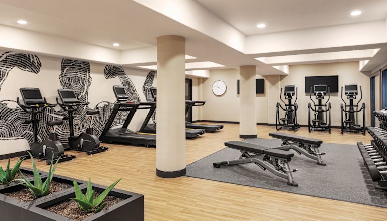 Löpband och vikter i fitnesscenter med HDTV