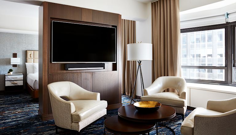 Guest Suite Lounge Area with Armchairs, Coffee Table and Wall Mounted HDTV