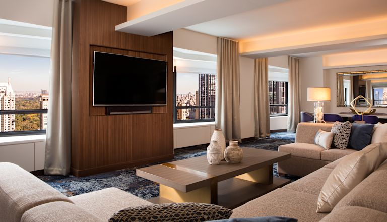 Suite living area with comfortable seating, wall mounted TV and views over the city