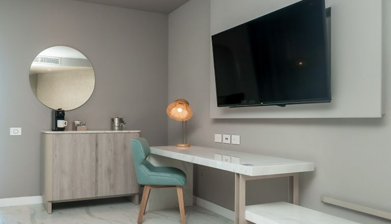 habitación con escritorio, televisor, área de bar con fregadero