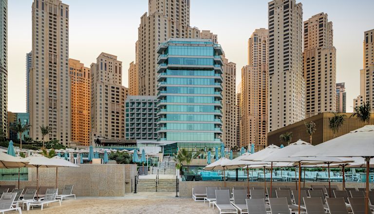 Hotel exterior with loungers and surrounding buildings