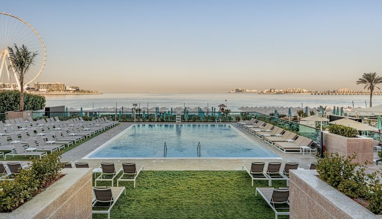 Outdoor pool with loungers, sea view and ferris wheel