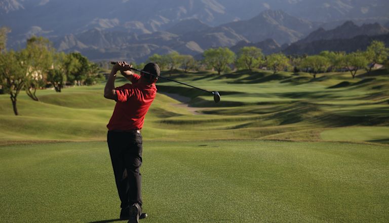 Golfer Swinging Club on Golf Course