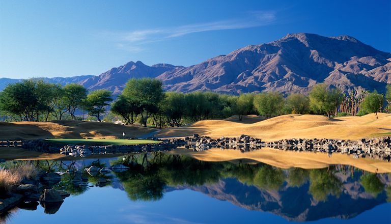 Panoramic view over a lake with mountains in the background. Location is TPC Stadium Course at PGA WEST